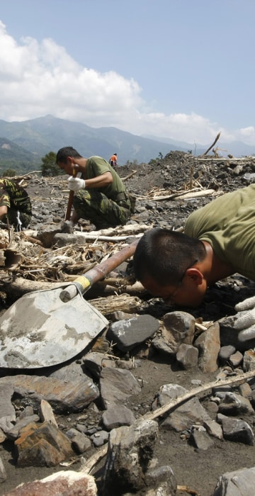 Image: A soldier smells the ground while looking for the bodies of flood victims in the mudslide-affected village of Sinkai, following Typhoon Morakot in Kaohsiung County
